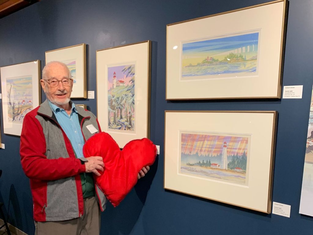 Artist Graham Scholes in the gallery of the Maritime Museum of BC with his lighthouse series of woodblock prints